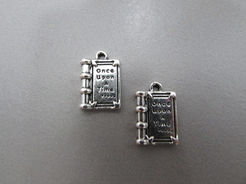 May include: Two silver-toned book charms with the words "Once Upon A Time" engraved on them.