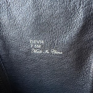 May include: Close-up of a black leather boot interior. The text "DEVI4 7.5M Made in China" is visible. The leather has a textured, wrinkled appearance.