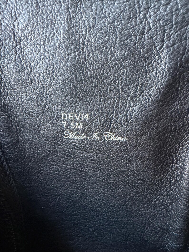 May include: Close-up of a black leather boot interior. The text "DEVI4 7.5M Made in China" is visible. The leather has a textured, wrinkled appearance.