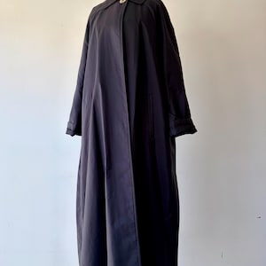 以下が含まれることがあります： クラシックなデザインの、長い濃いネイビーブルーのコート。 コートは襟、シングルボタン留め、長袖が特徴です。 無地の白い背景にマネキンで展示されています。