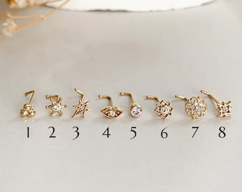May include: Eight gold nose rings with different designs, including a star, a lip, a flower, and a circle of small stones. The rings are numbered 1 through 8.