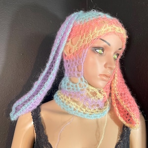 Puede incluir: Un gorro de crochet de color arcoíris pastel con largas orejeras. El gorro está hecho de un hilo suave y ligero y tiene un diseño delicado y calado.