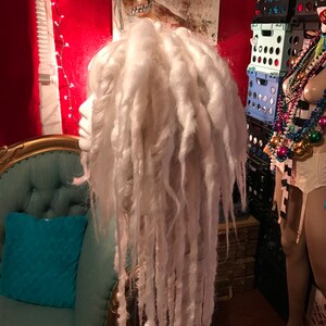 Puede incluir: Peluca de rastas sint&eacute;ticas blancas con mechones largos y gruesos. La peluca est&aacute; peinada de forma suelta y fluida.