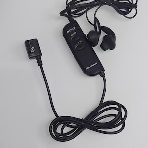 May include: Black Sony MDR-WME652 in-ear headphones with a wired remote control. The headphones have a black cord and earbud design. The remote control has the Sony logo and repeat button.