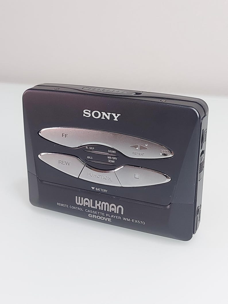 May include: A black Sony Walkman cassette player, model WM-EX570, with silver control buttons. The device has the word "WALKMAN" printed on the front, along with other text. The player is a vintage audio device.