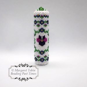 May include: A white beaded tube with a floral design in green, blue, pink, and gold. The tube has a green bead on top.  © Margaret Tobin Beading Past Times