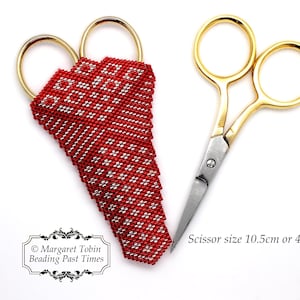 Puede incluir: Tijeras con mango dorado y hojas plateadas, junto a una funda de tijeras roja con cuentas y un patrón geométrico blanco. Las tijeras miden 10,5 cm de largo. La imagen incluye el texto "Margaret Tobin Beading Past Times".