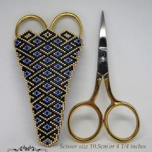 May include: A gold-colored scissor holder with a blue and gold geometric pattern. The holder is made of beads and is designed to hold a pair of small scissors. The scissors are 4 1/4 inches long and are shown next to the holder.  The text "Scissor size 10.5cm or 4 1/4 inches" is visible below the scissors.