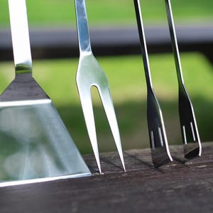 May include: Four silver grilling tools, including a spatula, two forks, and a pair of tongs.