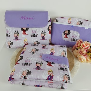 Puede incluir: Tres artículos de tela color lavanda con un estampado de villanos de dibujos animados. Los artículos incluyen una funda con solapa, una funda más pequeña y una manta acolchada. El nombre "Mavi" está escrito en la solapa y la manta. Un ramo de rosas rosas está cerca.