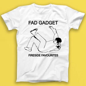 May include: White t-shirt with a black and white illustration of a person falling backwards. The text "FAD GADGET" and "FIRESIDE FAVOURITES" is printed on the shirt.