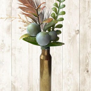 Boutonnière de latón con forma de casquillo de bala y plumas de faisán.