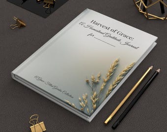 Può includere: Un diario con copertina rigida intitolato "Harvest of Grace: A Homestead Gratitude Journal" con un design a spighe di grano. Sono presenti anche matite dorate e nere e fermagli dorati.
