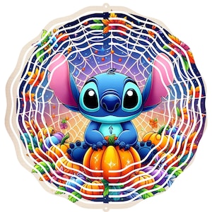 Op de afbeelding: Een ronde, gelaagde decoratie met Stitch van Lilo & Stitch. Stitch, blauw met grote ogen, zit op een oranje pompoen omringd door andere pompoenen en herfstbladeren. Een spinnenwebontwerp is op de achtergrond.
