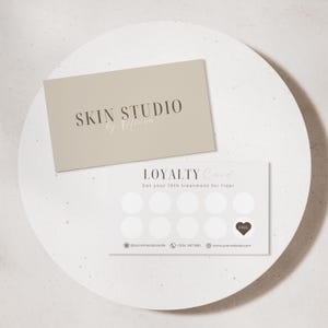 May include: Two cards on a white surface. The top card is beige with the text "SKIN STUDIO by Olivia" in brown. The bottom card is white with the text "LOYALTY Card" and "Get your 10th treatment for free!" with a heart and the word "FREE".