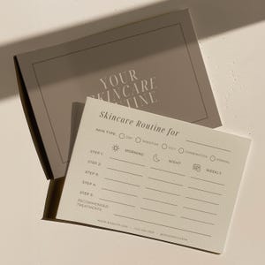 Peut inclure: Une carte de routine de soins de la peau beige clair avec le texte "Skincare Routine for" et des sections pour le type de peau, le matin, le soir et les étapes hebdomadaires. La carte est accompagnée d'une boîte assortie, avec le texte "YOUR SKINCARE TINE" sur la boîte.