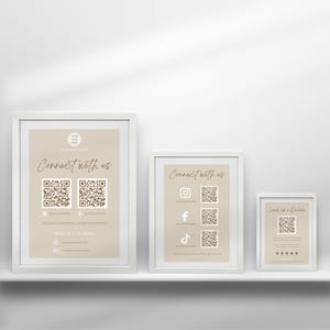 May include: Three white picture frames with beige mats and black text on a white shelf. The frames contain QR codes and social media icons. The text in the frames reads "Connect with us".
