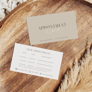 Pode incluir: Dois cartões de compromisso. Um cartão é bege claro com as palavras "APPOINTMENT Card" impressas. O outro cartão é branco com as palavras "YOUR APPOINTMENTS" impressas. Ambos os cartões têm um identificador de mídia social e um endereço de site.