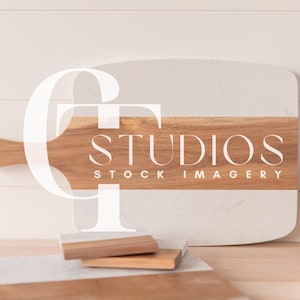 May include: A white marble and wood cutting board with a wooden handle. The board has the text "STUDIOS STOCK IMAGERY" printed on it.
