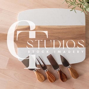 May include: A wooden and marble cheese board with a handle and four cheese knives. The board has the text "STUDIOS STOCK IMAGERY" printed on it.