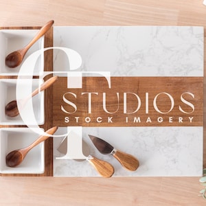 May include: A white marble serving tray with a wooden frame and three small white bowls. The tray has a wooden divider with the text "STUDIOS STOCK IMAGERY". The tray is on a light wood surface.