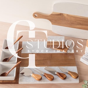 May include: A white and brown marble serving tray with a wooden cutting board, four small white bowls with wooden spoons, and five small wooden cheese knives. The tray is on a light wood surface.