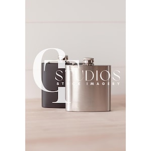 Puede incluir: Dos matraces metálicos, uno plateado y otro negro, sobre una superficie de madera clara. El matraz plateado tiene el texto "Studios Stock Imagery".