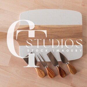 May include: A rectangular wooden cutting board with a white marble section and a handle, accompanied by four cheese knives. The board has a light brown wood grain, and the knives have wooden handles and silver blades. The image includes the text "STUDIOS STOCK IMAGERY".