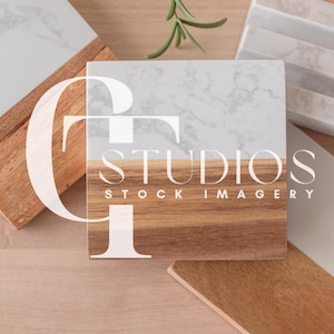 Puede incluir: Dos posavasos de madera con una parte superior de mármol blanco. Los posavasos están hechos de madera natural de color marrón claro. Los posavasos están dispuestos sobre una superficie de madera marrón claro. El texto "STUDIOS STOCK IMAGERY" está impreso en blanco en los posavasos.