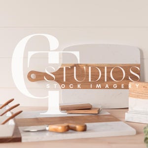 Puede incluir: Una colección de artículos de cocina y servicio, que incluye una tabla de cortar rectangular de mármol y madera, pequeños cuencos blancos para servir con cucharas de madera y una tabla de quesos de mármol y madera. La imagen tiene el texto "STUDIOS STOCK IMAGERY".
