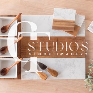 May include: A white marble and wood serving tray with three small white bowls and wooden spoons. The tray has a brown wood border and the text "STUDIOS STOCK IMAGERY" is printed on the wood.