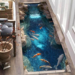 May include: A rectangular floor decal featuring a 3D illusion of a koi pond with a small waterfall, rocky edges, and several orange, white, and grey koi fish swimming in clear blue water, designed to create a realistic aquatic scene.