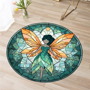 May include: Circular rug with a stained-glass effect, depicting a fairy. The fairy has orange wings and a green dress. The rug's border is teal, and the background is a mosaic of green and white shapes. The rug is on a light brown wooden floor.