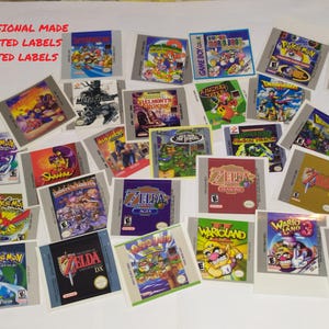 以下が含まれることがあります： ゲームボーイカラーのビデオゲームカートリッジ用の、ラミネート加工されたプレカットラベルのコレクションです。「ポケモン」、「ゼルダ」、「ワリオランド」など、さまざまなゲームのカラフルなグラフィックとテキストが特徴です。「PROFESSIONAL MADE」の文字が見えます。