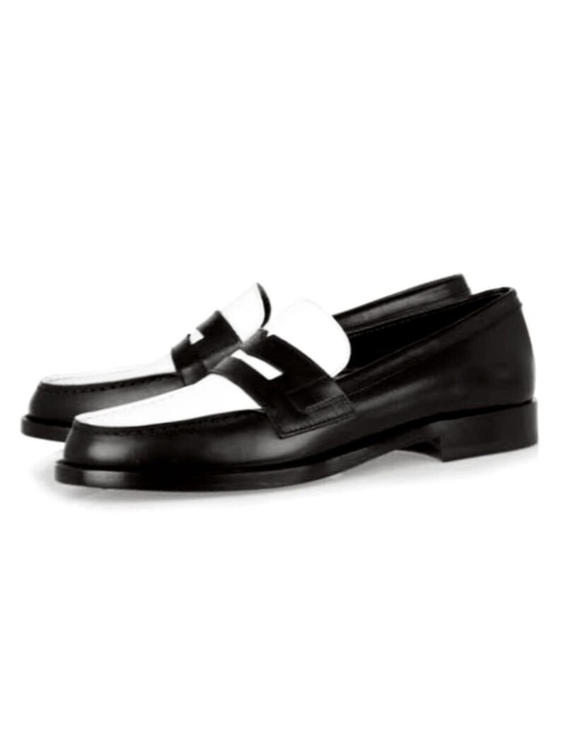 May include: Black leather loafers with a white leather panel across the toe. The loafers have a classic penny loafer design with a single strap across the top.