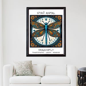 May include: A framed art print featuring a stylized dragonfly illustration. The dragonfly has blue and orange wings, a blue body, and is set against a circular, patterned background. Text at the top reads "SPIRIT ANIMAL" and below the dragonfly, "DRAGONFLY" with the words "TRANSFORMATION WISDOM RESILIENCE".