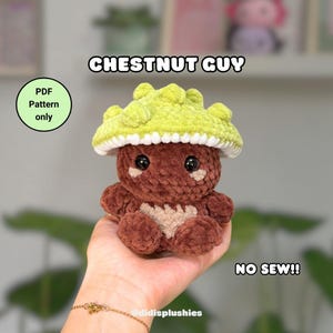 Puede incluir: Un peluche de ganchillo hecho a mano con forma de castaña. El peluche tiene un cuerpo marrón, un gorro de seta verde claro y un borde blanco. El texto "CHESTNUT GUY" y "NO SEW!!" son visibles. Patrón PDF disponible.