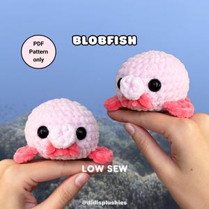 Peut inclure: Deux peluches blobfish crochetées rose clair avec des yeux de sécurité noirs et des lèvres rose foncé. L'image contient le texte BLOBFISH, PDF Pattern only, LOW SEW et @didisplushies. Les peluches ont un aspect en fil texturé doux.