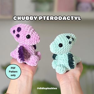 Puede incluir: Dos peluches de ganchillo con forma de pterodáctilo, uno de color morado claro y otro verde claro, ambos con alas y manchas de color morado o verde oscuro, ojos de seguridad negros y el texto CHUBBY PTERODACTYL y PDF Pattern only.