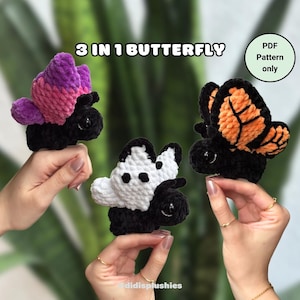 May include: Three crocheted butterfly amigurumi toys. The butterflies are black with different colored wings: purple and pink, white with black spots, and orange. The text "3 IN 1 BUTTERFLY" and "PDF Pattern only" is visible in the image.