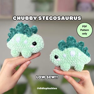 May include: Two handmade, light green crochet stegosaurus plushies with dark green spines and white spots. The text "CHUBBY STEGOSAURUS" and "LOW SEW!!" are displayed. A small circle reads "PDF Pattern only". The shop's name, "@didisplushies", is also visible.