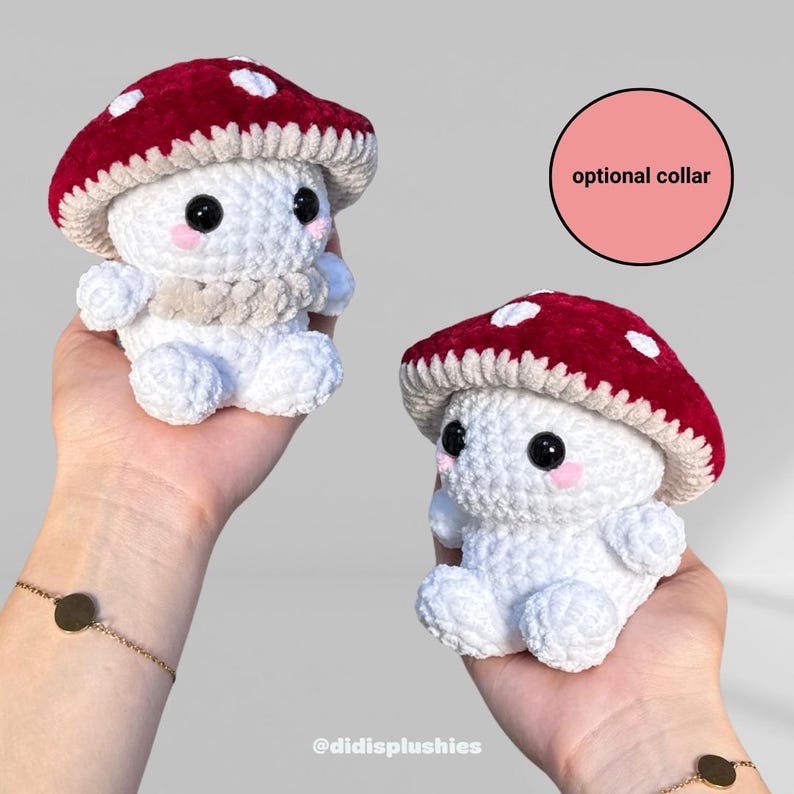 Op de afbeelding: Twee handgemaakte gehaakte paddenstoelknuffels. Elke knuffel heeft een rode kap met witte stippen, een witte body en een beige kraag. De knuffels hebben zwarte ogen en roze wangen. De tekst "optional collar" staat in een roze cirkel.