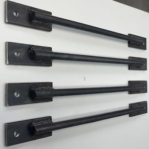May include: Four black metal rods with flat ends, each with a hole drilled through the flat end. The rods are arranged vertically, with the top rod being the longest and the bottom rod being the shortest.