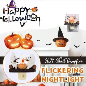 May include: A white ceramic nightlight featuring two ghosts roasting marshmallows over a campfire. The nightlight is plugged into an outlet and has a flickering flame effect. The text "2024 Ghost Campfire Flickering Nightlight" is visible in the image.