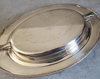 May include: A silver oval serving dish with a lid. The lid has a decorative design in the center.