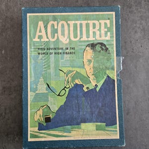 May include: Vintage board game box titled "ACQUIRE" with a teal border. The cover features a man in a blue suit holding glasses, with text "HIGH ADVENTURE IN THE WORLD OF HIGH FINANCE". The background has a cityscape in shades of green and blue.
