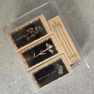 May include: A set of four wooden stamps with black ink designs. The stamps feature floral and tree designs with inspirational quotes. The quotes are "Spread your love everywhere you go", "The amen of nature is always a heart that gives also gathers", "Flower - Emerson", and "Heart that gives also gathers".