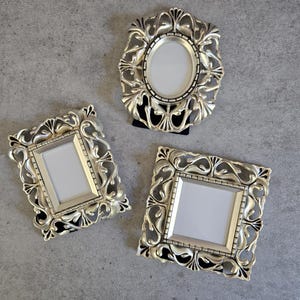 May include: Three ornate gold picture frames with intricate designs. The frames are empty and ready to display photos or artwork.