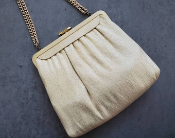 May include: A gold metallic clutch purse with a chain strap. The purse has a pleated design and a clasp closure.