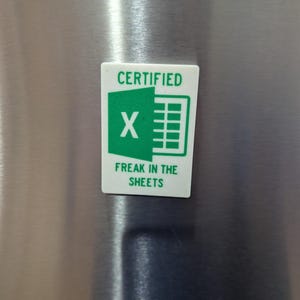 May include: A white rectangular sticker with green text and graphics. The top text reads "CERTIFIED" above a green "X" and a spreadsheet icon. Below, the text reads "FREAK IN THE SHEETS".